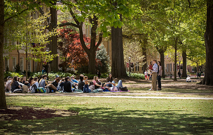 A group of students sits on the Horseshoe as part of a class held outside