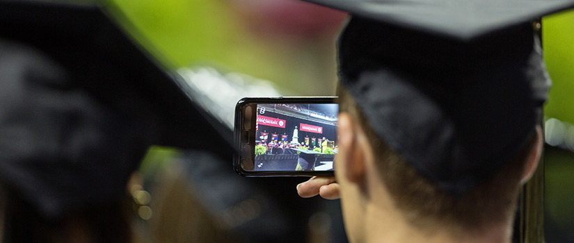 student with camera phone at graduation