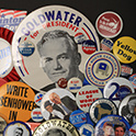 Close up of various pin-back buttons, declaring support for certain organizations or political campaigns. Legible text on different buttons read, “Goldwater for president,” “Yellow Dog,” “League of Women Voters,” and “Write Eisenhower in.”
