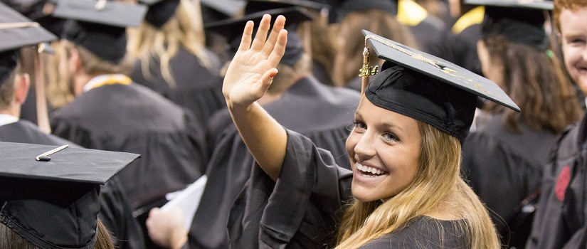 Graduate in cap and gown waves to her friends