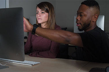 Two students pointing at a computer screen