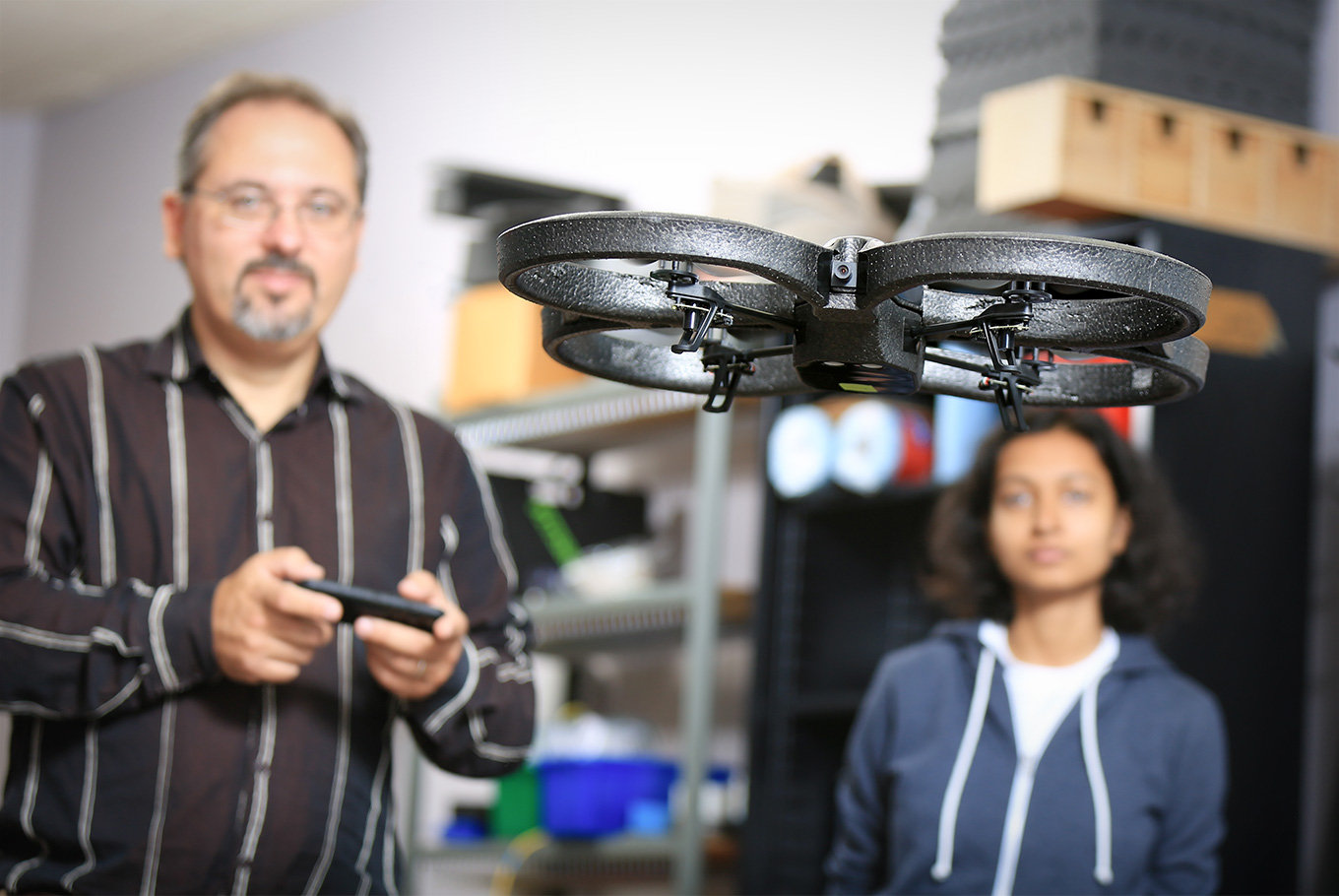 Teacher and student control drone which is flying in air.