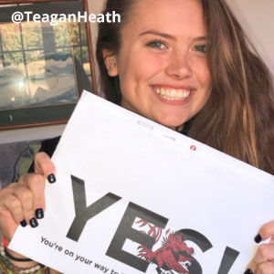 Image provided by @teaganheath of a young woman with brown hair smiling and holding an acceptance envelope under her chin that says, Yes!