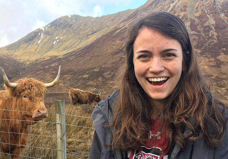 Kristen Kauffman next to hairy cow in the mountains of Scotland