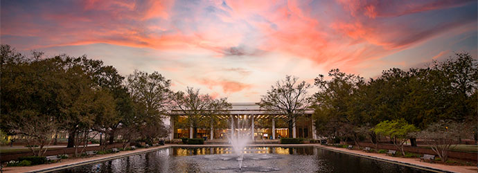 Thomas Cooper library sits behind the fountains of the reflecting pond in front of a stunning purple and red sunset.