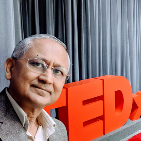 Amit stands in front of the TEDx sign.