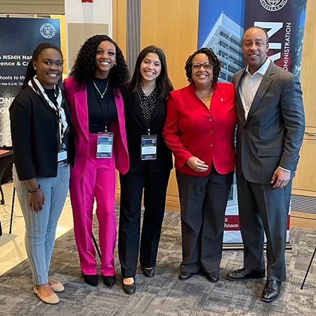 Four members of the National Society of Minorities in Hospitality attend a conference and pose with Evan Frazier, one of the NSMH founders.