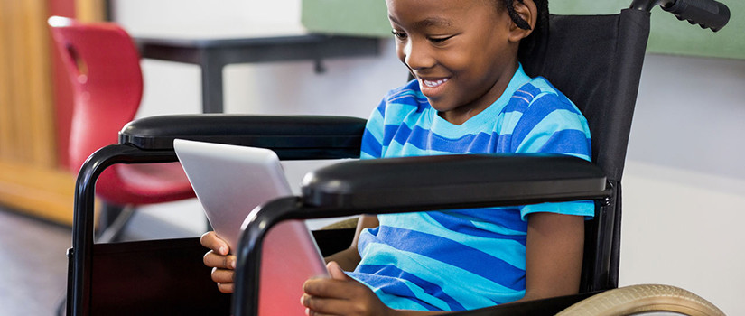 A child in a wheelchair uses his tablet