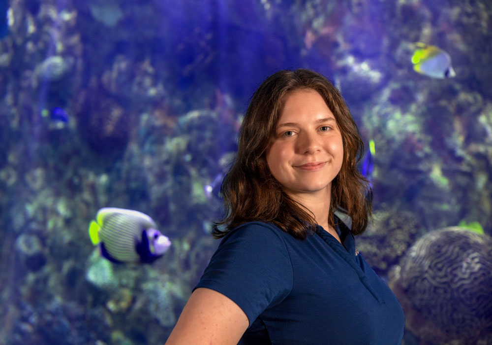 Sarah Weaver stands in front of a large aquarium