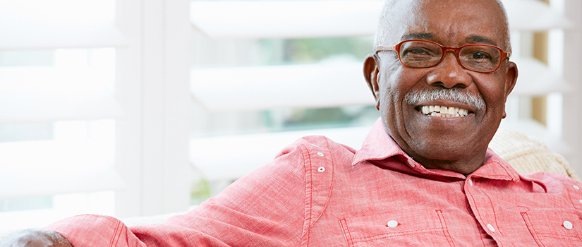 Image of a man sitting on a couch smiling with his arm stretched across the back of the couch.