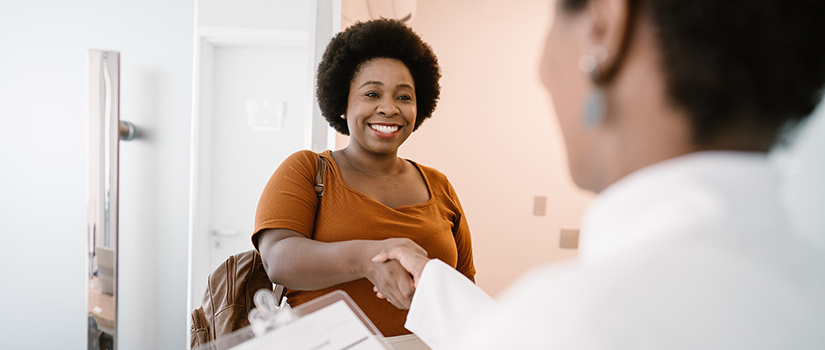 Image of a patient smiling and shaking a health care provider's hand. 