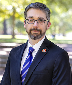 Headshot of Leonardo Bonilha outdoors. He is wearing a suit and tie. 