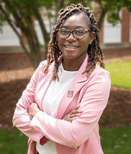 Headshot of Takia Woods in a suit outdoors.