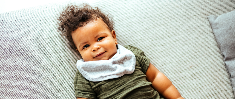 cute baby with fuzzy brown hair laying on blanket 