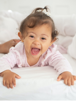 little baby smiling on a pink blanket
