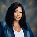 Anja Wilson, a Black woman in a blue blazer, smiles at the camera for a professional headshot