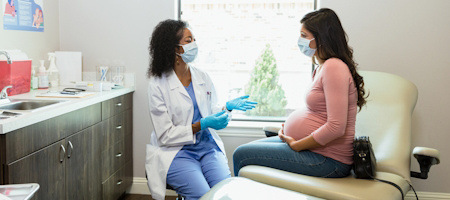 Doctor talking with pregnant woman in masks