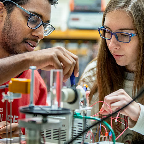 mechanical engineering students examine piece of equipment