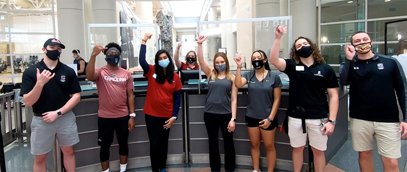 students do the spurs up sing in front of the service desk at the Strom Thurmond wellness and fitness center.