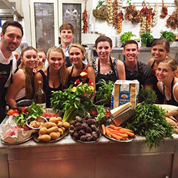 a roup of students in aprons, surrounding a table covered in fresh produce