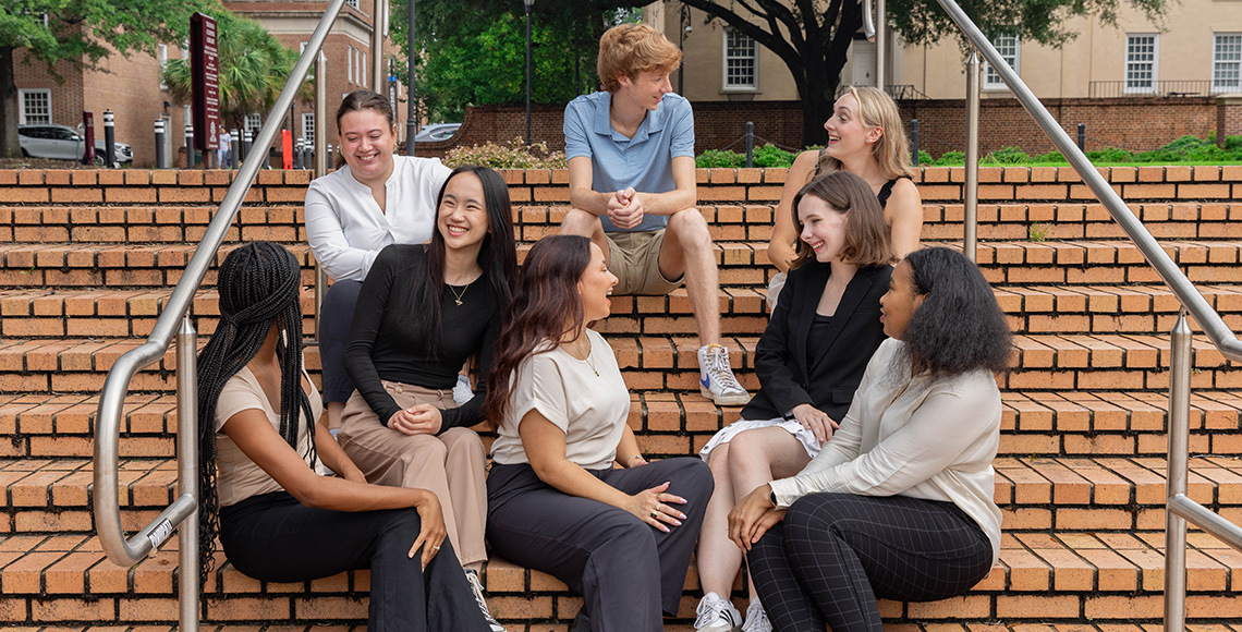 students sitting on steps looking at each other and smiling