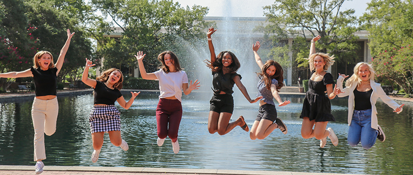 students jumping into the air in front of the fountain