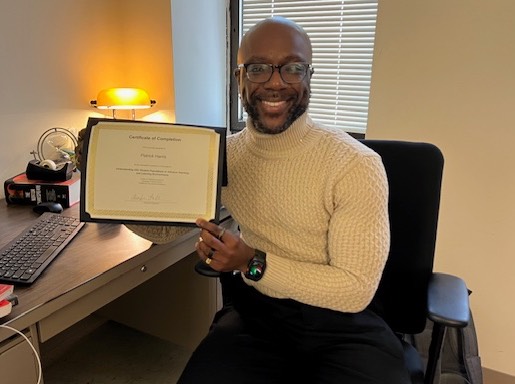 Man sitting in front of computer holding certificate