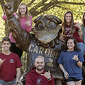 students taking pictures with a cocky statute