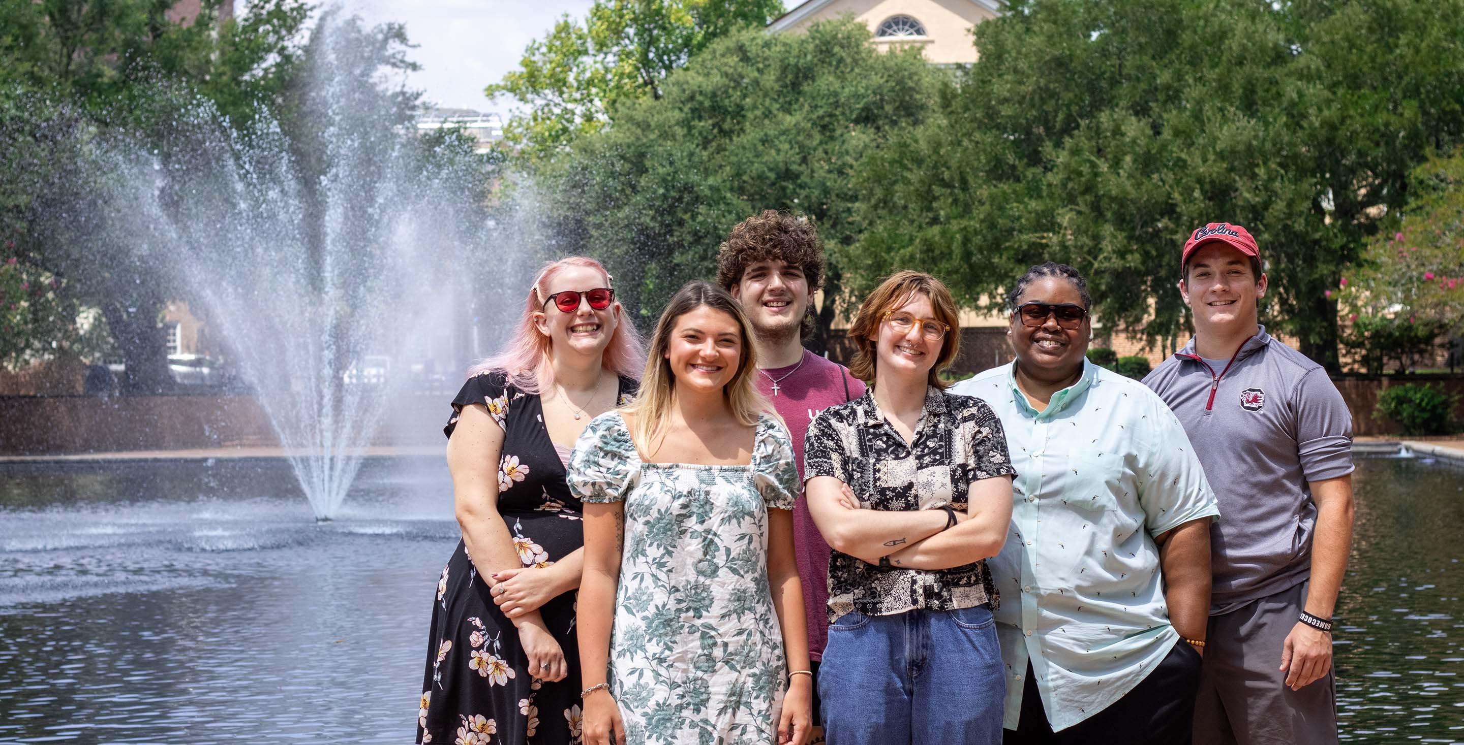 A group of students with diverse disabilities pose before the Thomas Cooper Library fountain.