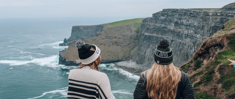 two students standing at Cliffs of Moher in Ireland looking into the water