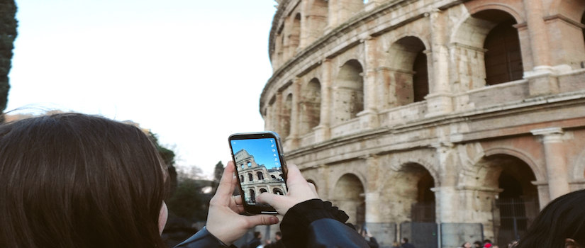 a student holding a phone up to take a photo of the colliseum
