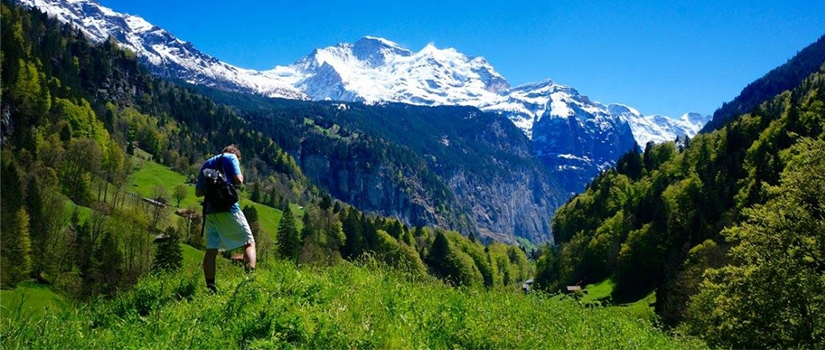 Student hiking on a mountain range with a snow-capped mountain in the distance