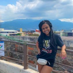 Women stands against a railing with mountains in the background