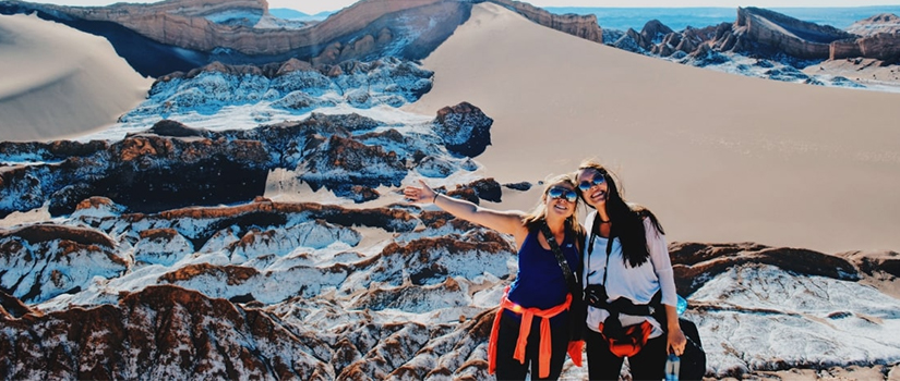 Two women hug in front of a mountain range