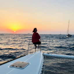 Girl overlooks the sunset while sitting on a boat