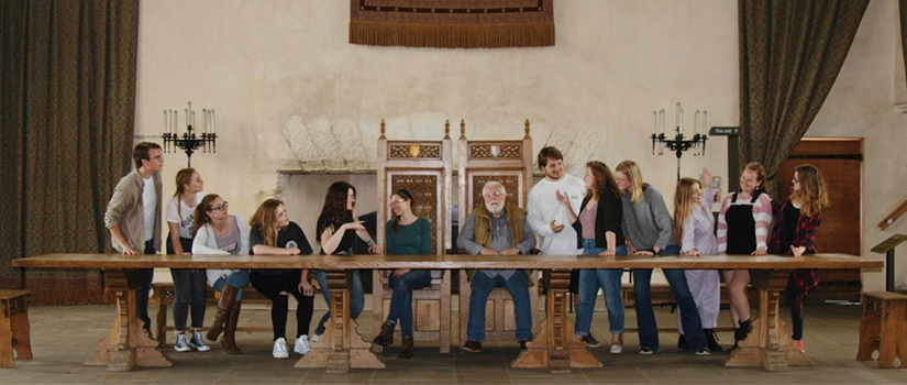 A group of students pose together like the last supper