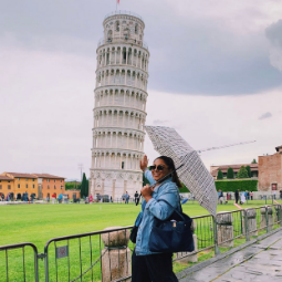 Woman holding an umbrella poses in front of the Pisa tower