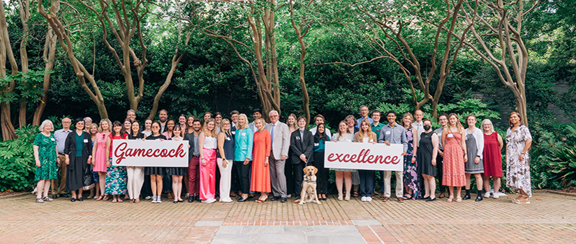 Large group of national fellowship winners with USC faculty, staff and President Amiridis holding up a sign that says, "Gamecock Excellence."
