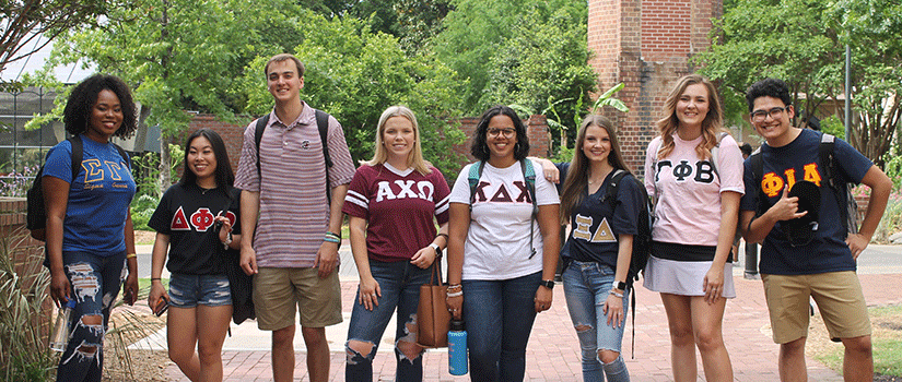 A group of Greek students spend time together walking through campus.