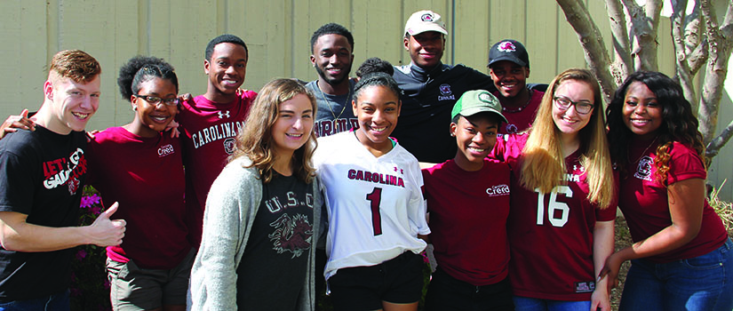 A group of Gamecock Gateway students wear Carolina gear as they pose for the camera.