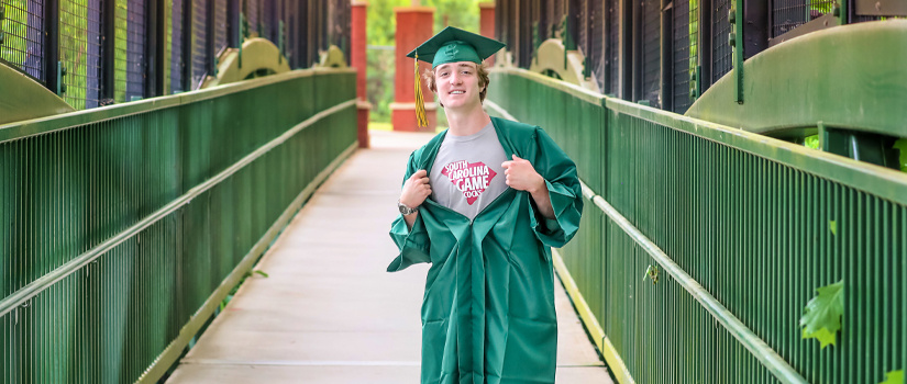 High school student wearing a cap and gown shows his Carolina shirt shining through