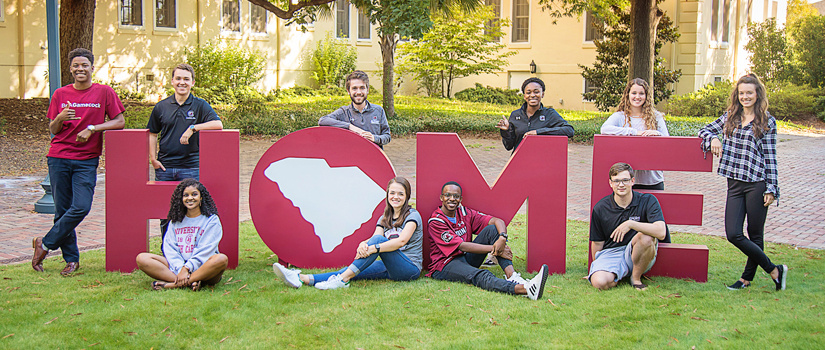 Carolina students surrounding large letters that spell HOME