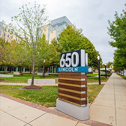A sign for 650 Lincoln sits in the foreground, with small trees and green space in front of an apartment building with multiple stories.