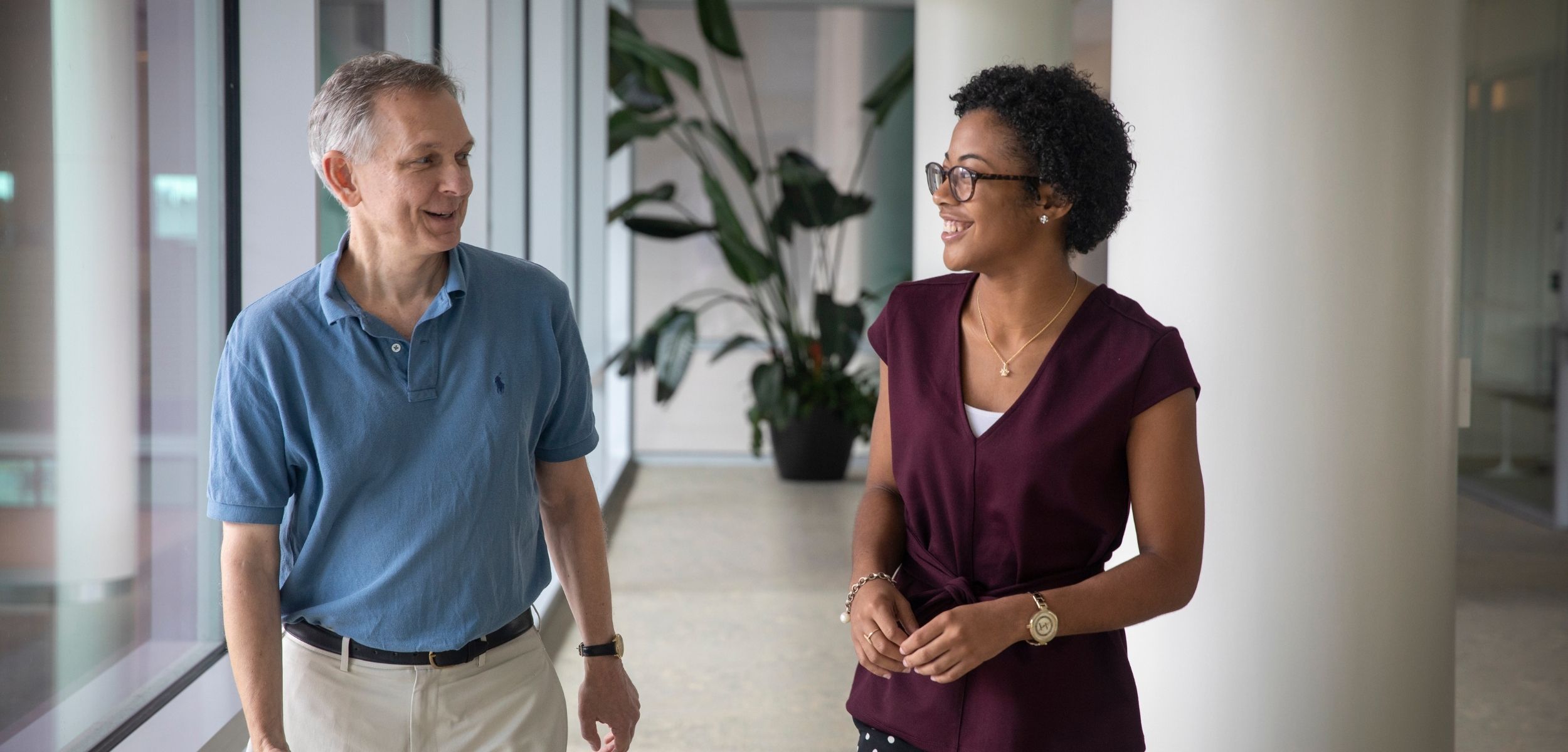 Staff member and student talking while walking down the hallway. 