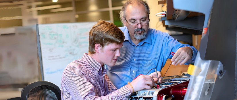 Student working at a lab desk with a mentor helping him