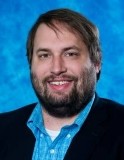 Mark Uline, smiling, wearing a dark blazer over a light blue button-down shirt.
