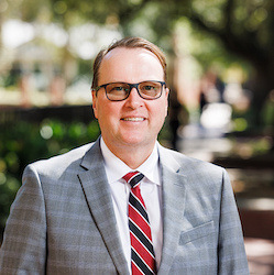 Portrait photo of USC Vice President for Research Julius Fridriksson in a grey plaid suit with garnet and black striped tie.