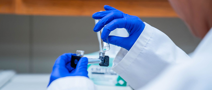 Student in rubber gloves experiments with a test tube