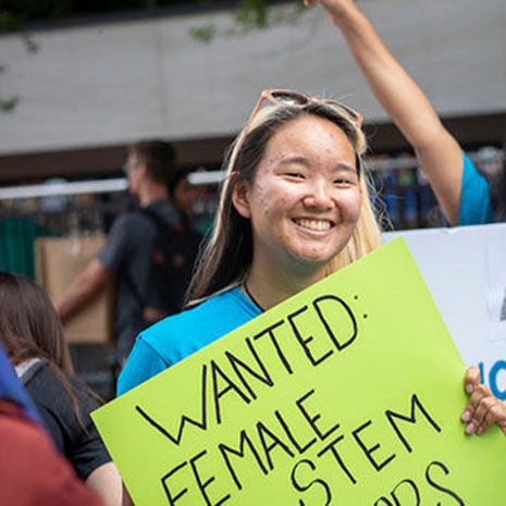 female student holds banner for Women in STEM student organization