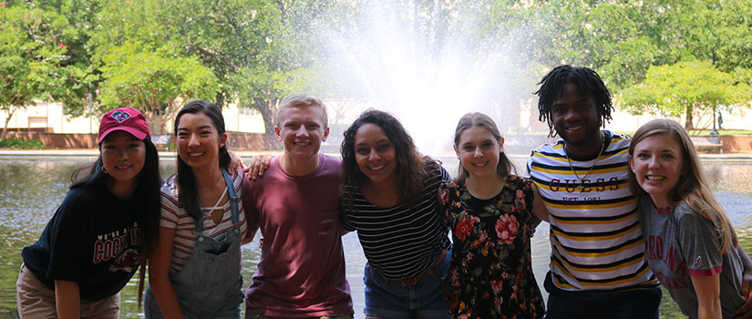 group of students posing in front of thomas cooper library fountain